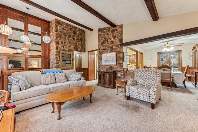 living room with ceiling fan with notable chandelier, beam ceiling, carpet floors, and french doors