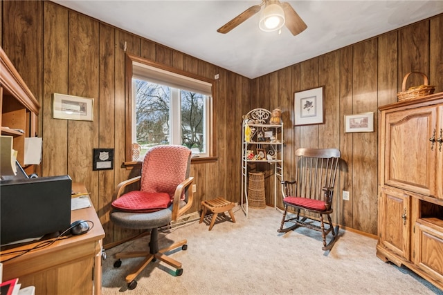 office with wooden walls, ceiling fan, and light colored carpet