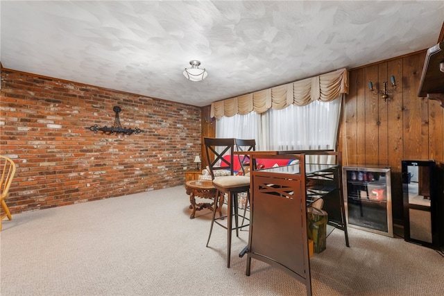 carpeted dining area featuring wooden walls and brick wall