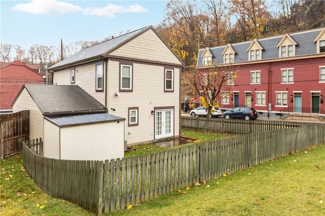 back of property featuring french doors and a lawn