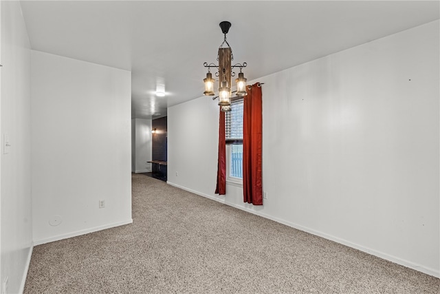 carpeted spare room featuring a notable chandelier