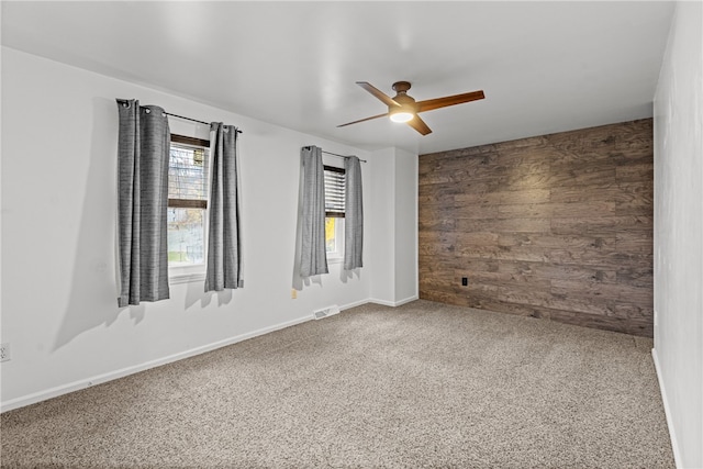 unfurnished room with carpet, ceiling fan, and wood walls