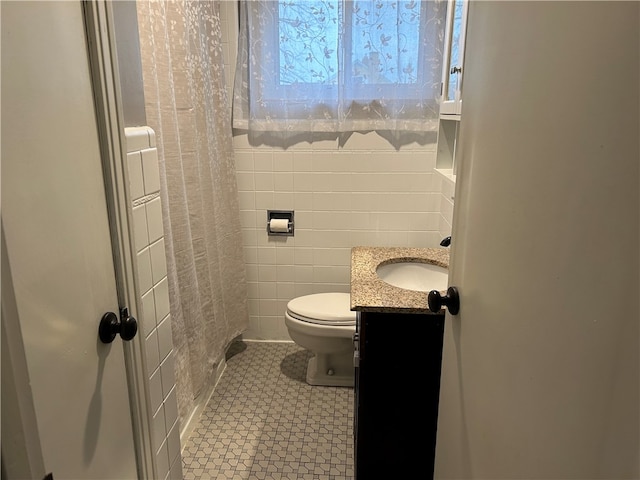 bathroom featuring walk in shower, vanity, tile walls, and toilet