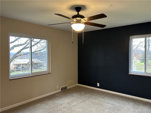 carpeted spare room with ceiling fan and a wealth of natural light