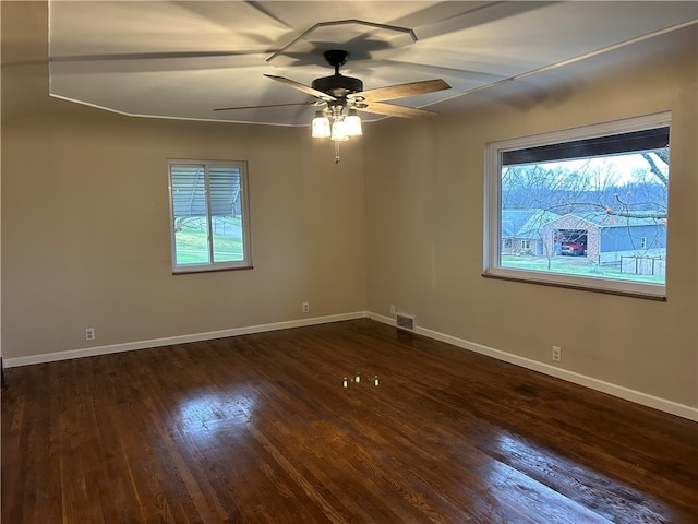 empty room with a wealth of natural light, dark hardwood / wood-style flooring, and ceiling fan