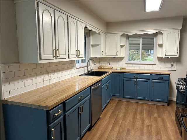 kitchen with white cabinets, wood counters, blue cabinets, and sink