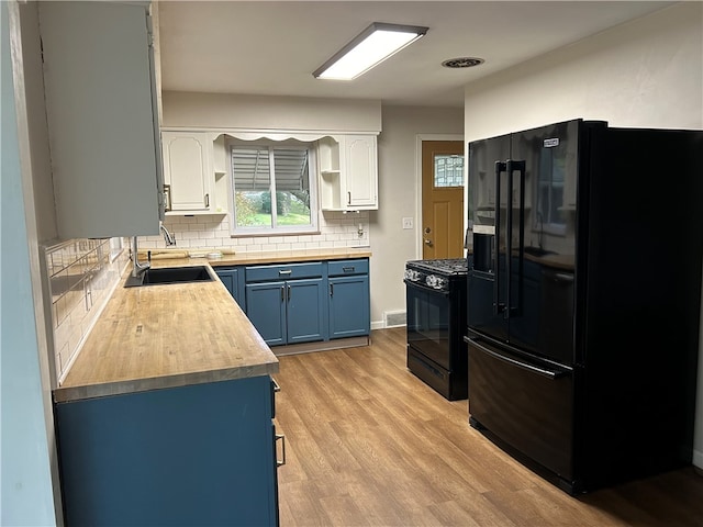 kitchen featuring wooden counters, blue cabinets, sink, black appliances, and white cabinetry