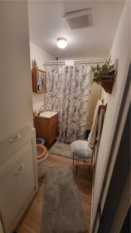 bathroom featuring curtained shower, vanity, wood-type flooring, and toilet