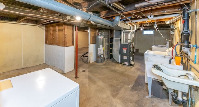 basement featuring separate washer and dryer, gas water heater, heating unit, and white fridge