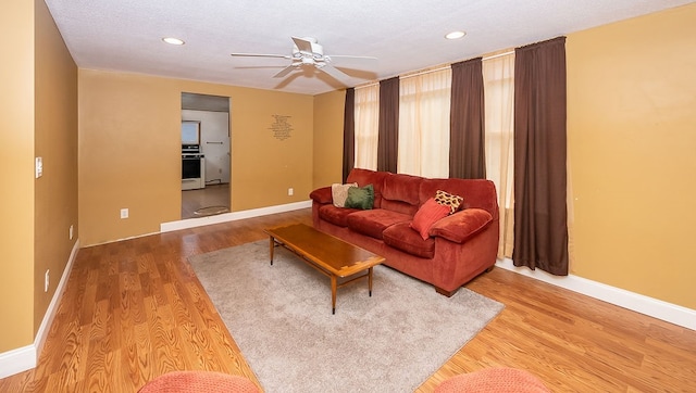 living room with ceiling fan, wood-type flooring, and a textured ceiling