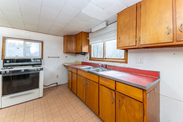 kitchen with light tile patterned floors, white range, plenty of natural light, and sink