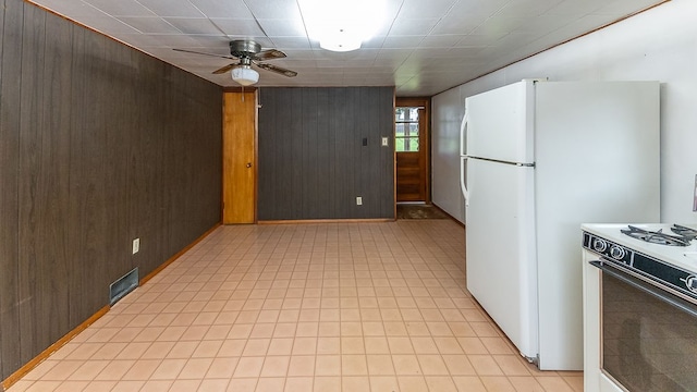 kitchen featuring wood walls, dark brown cabinets, ceiling fan, and white appliances