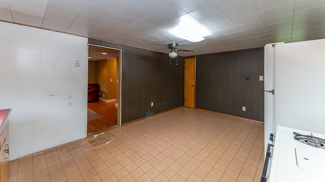 spare room with ceiling fan and wooden walls