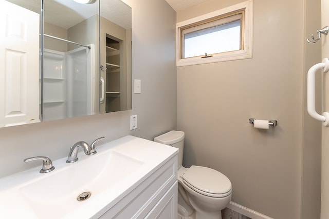 bathroom featuring a shower, vanity, and toilet