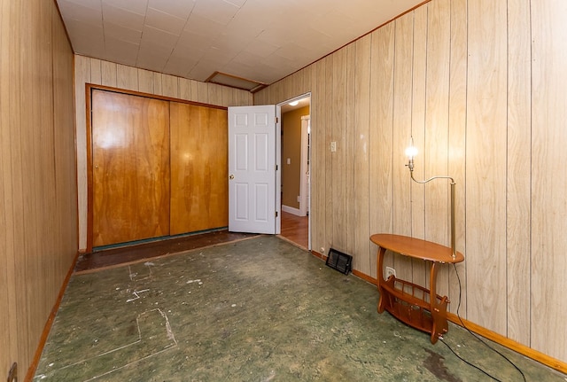 unfurnished bedroom with wood walls and a closet