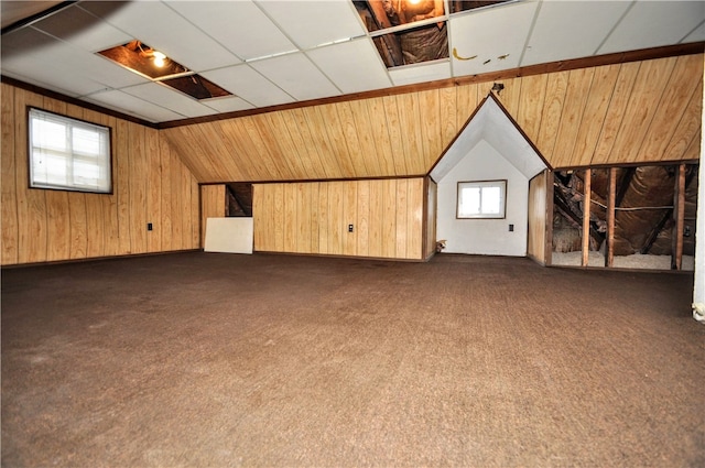 additional living space with wooden walls, lofted ceiling, and dark colored carpet