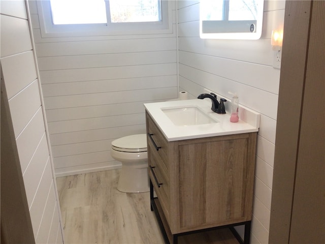 bathroom with vanity, toilet, wood-type flooring, and wooden walls