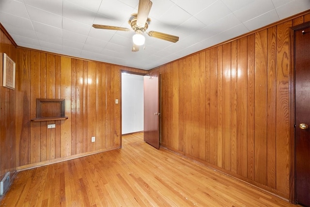 unfurnished room featuring light hardwood / wood-style floors and wooden walls