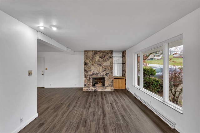 unfurnished living room featuring a fireplace, a baseboard radiator, and dark hardwood / wood-style floors