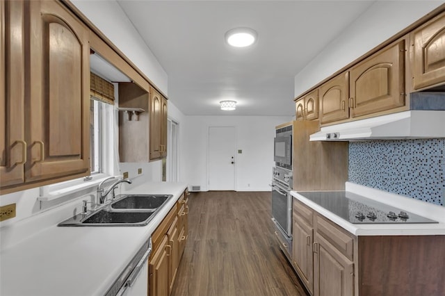 kitchen with dark hardwood / wood-style floors, stainless steel oven, sink, and tasteful backsplash