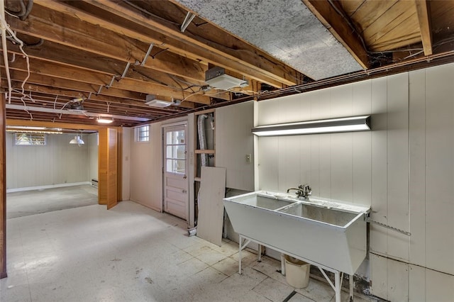 basement with a wealth of natural light, wood walls, and sink