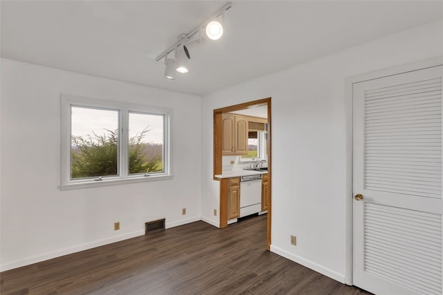 spare room with rail lighting and dark hardwood / wood-style floors