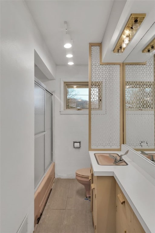 full bathroom featuring tile patterned flooring, vanity, enclosed tub / shower combo, and toilet