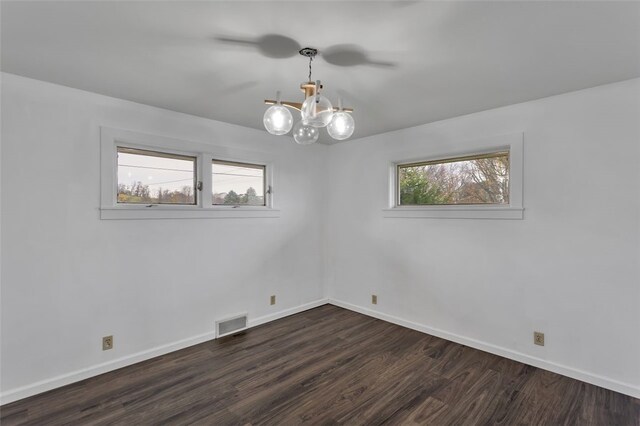 unfurnished room featuring a wealth of natural light, dark hardwood / wood-style floors, and a notable chandelier