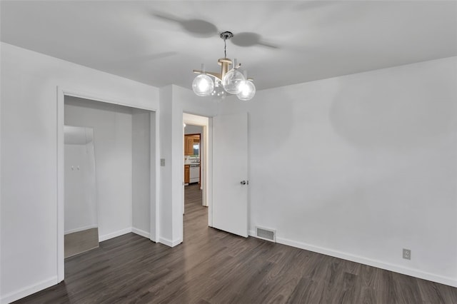 empty room featuring dark hardwood / wood-style flooring and a chandelier