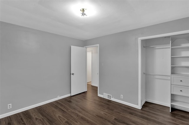 unfurnished bedroom with a closet and dark hardwood / wood-style flooring