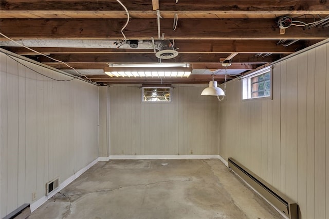 basement with wooden walls and a baseboard heating unit