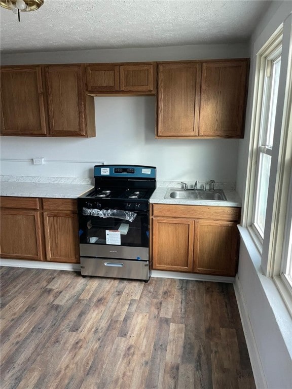 kitchen with a textured ceiling, sink, stainless steel stove, and dark wood-type flooring