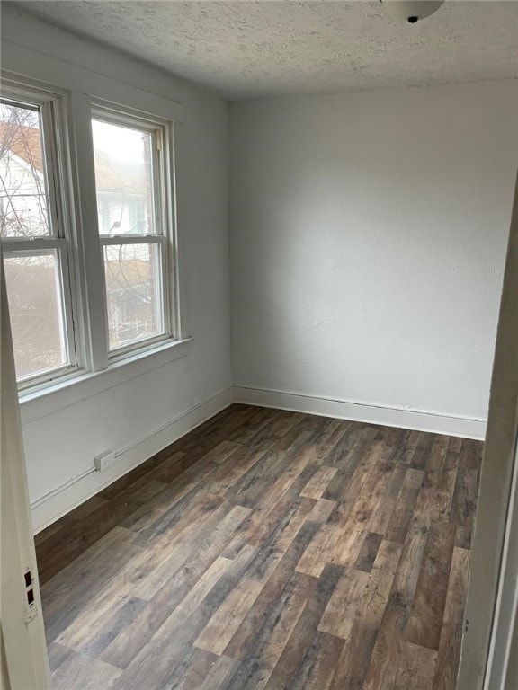 unfurnished room featuring dark hardwood / wood-style flooring and a textured ceiling