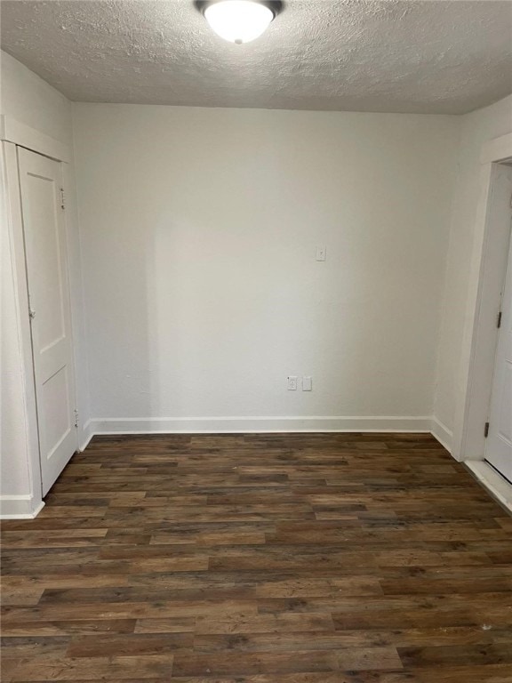 empty room with a textured ceiling and dark wood-type flooring