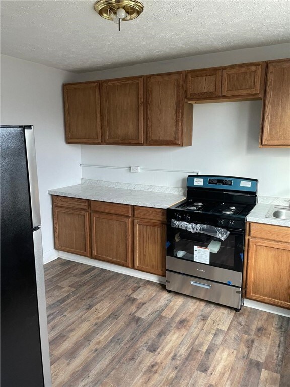 kitchen featuring dark hardwood / wood-style floors, sink, a textured ceiling, and appliances with stainless steel finishes