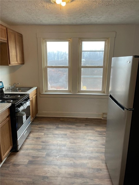 kitchen with hardwood / wood-style floors, sink, appliances with stainless steel finishes, and a textured ceiling