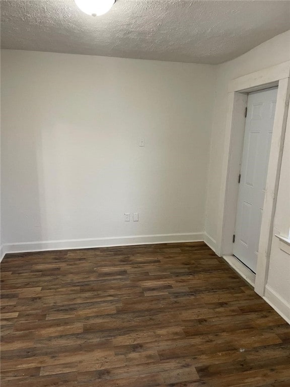 unfurnished room with a textured ceiling and dark wood-type flooring