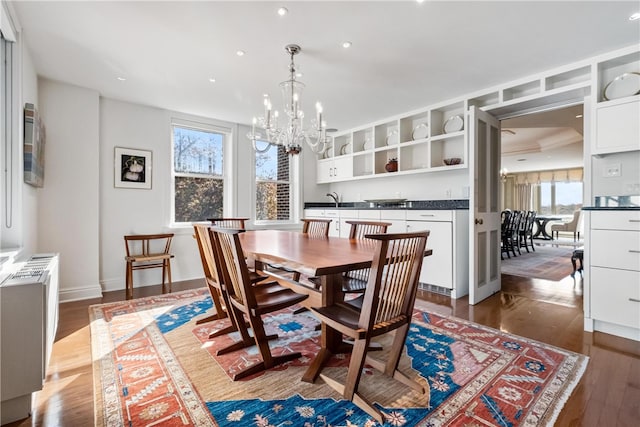 dining room featuring a healthy amount of sunlight, dark wood-type flooring, radiator, and an inviting chandelier