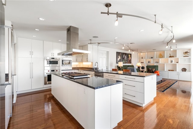 kitchen featuring sink, a kitchen island, wood-type flooring, island range hood, and white cabinets