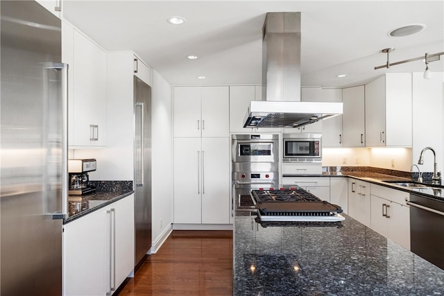 kitchen with island exhaust hood, built in appliances, and white cabinets