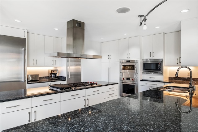 kitchen featuring sink, built in appliances, dark stone countertops, extractor fan, and white cabinets