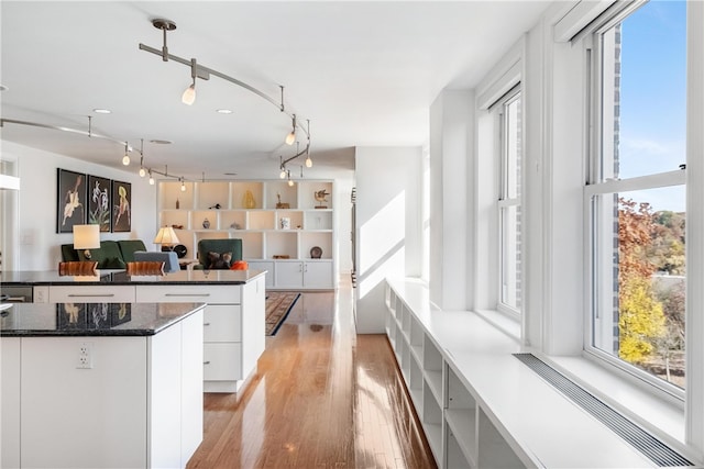 kitchen with white cabinets, a kitchen island, and light wood-type flooring