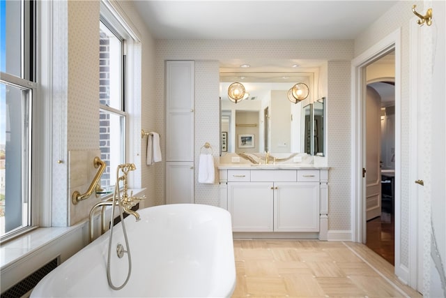 bathroom featuring a wealth of natural light, a bathtub, vanity, and parquet flooring