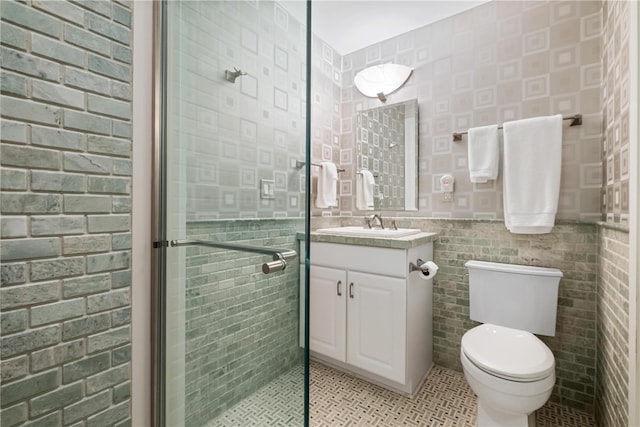 bathroom with vanity, toilet, a shower with door, and tile walls