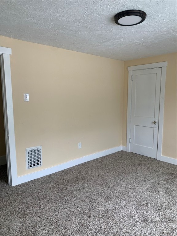 spare room featuring carpet flooring and a textured ceiling