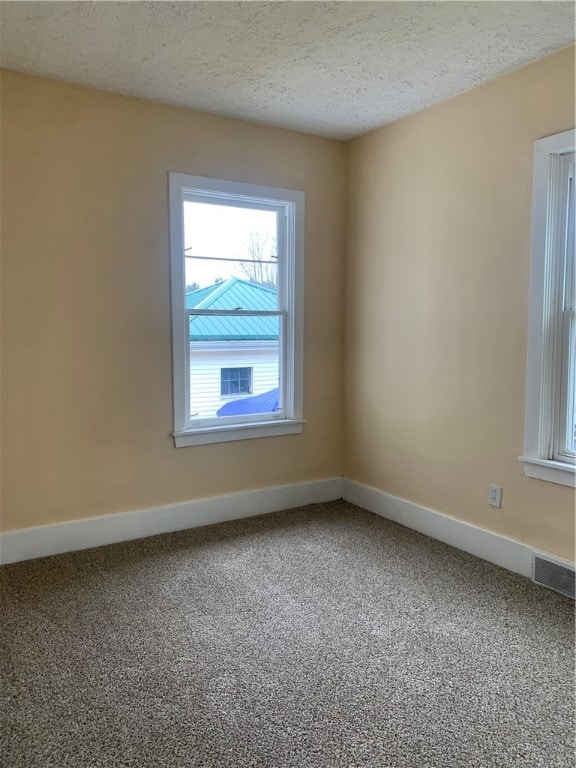 carpeted empty room with a textured ceiling