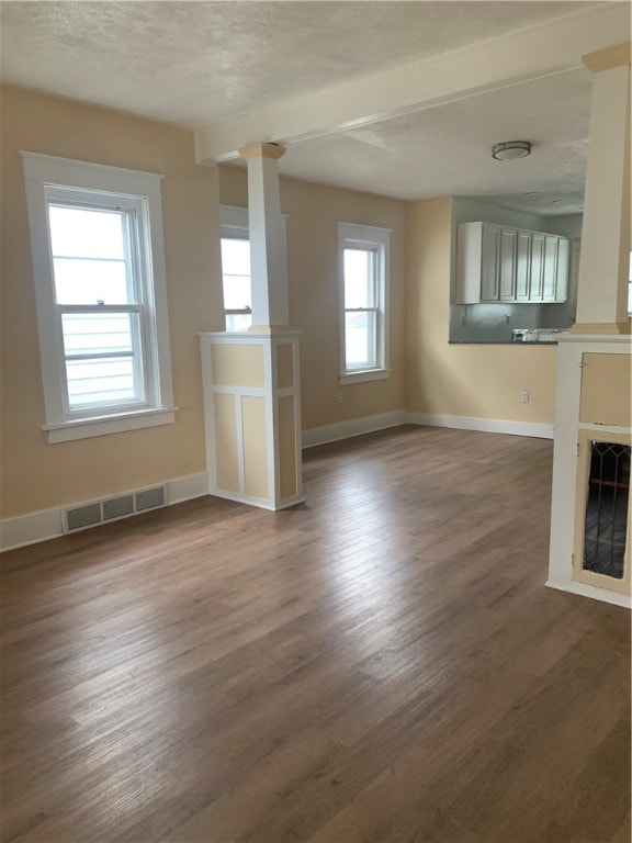 unfurnished living room featuring plenty of natural light, dark hardwood / wood-style flooring, and a textured ceiling