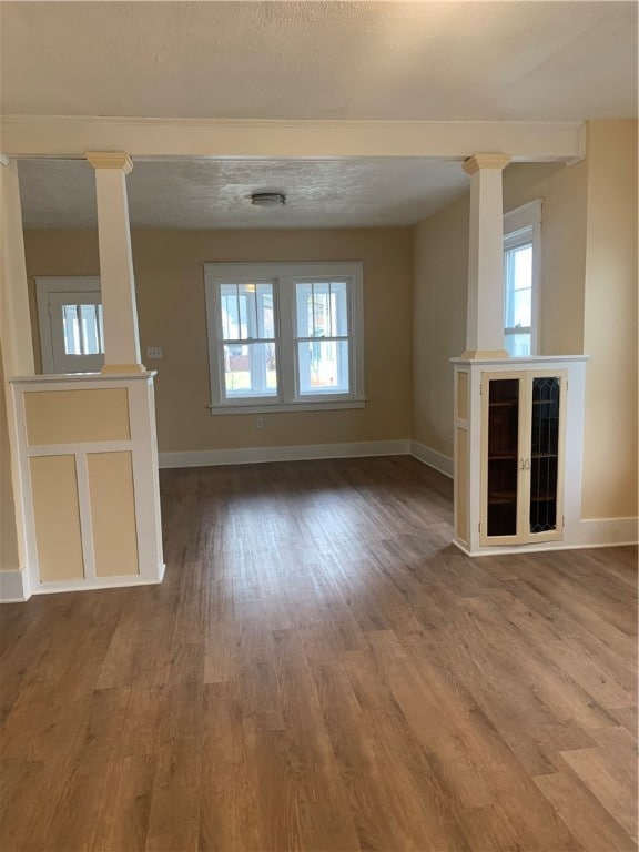 unfurnished living room with a textured ceiling, hardwood / wood-style flooring, and a wealth of natural light