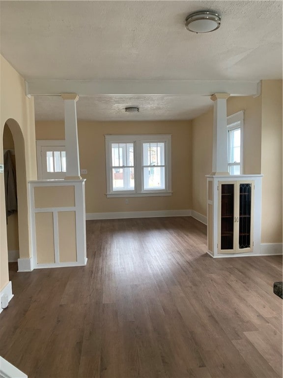 unfurnished living room with wood-type flooring, a textured ceiling, and a wealth of natural light