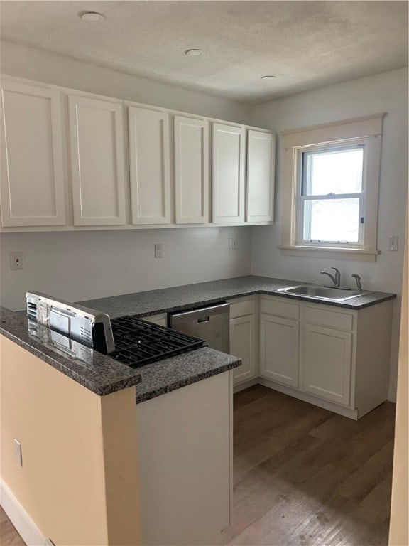 kitchen with white cabinets, stainless steel dishwasher, sink, and light hardwood / wood-style flooring